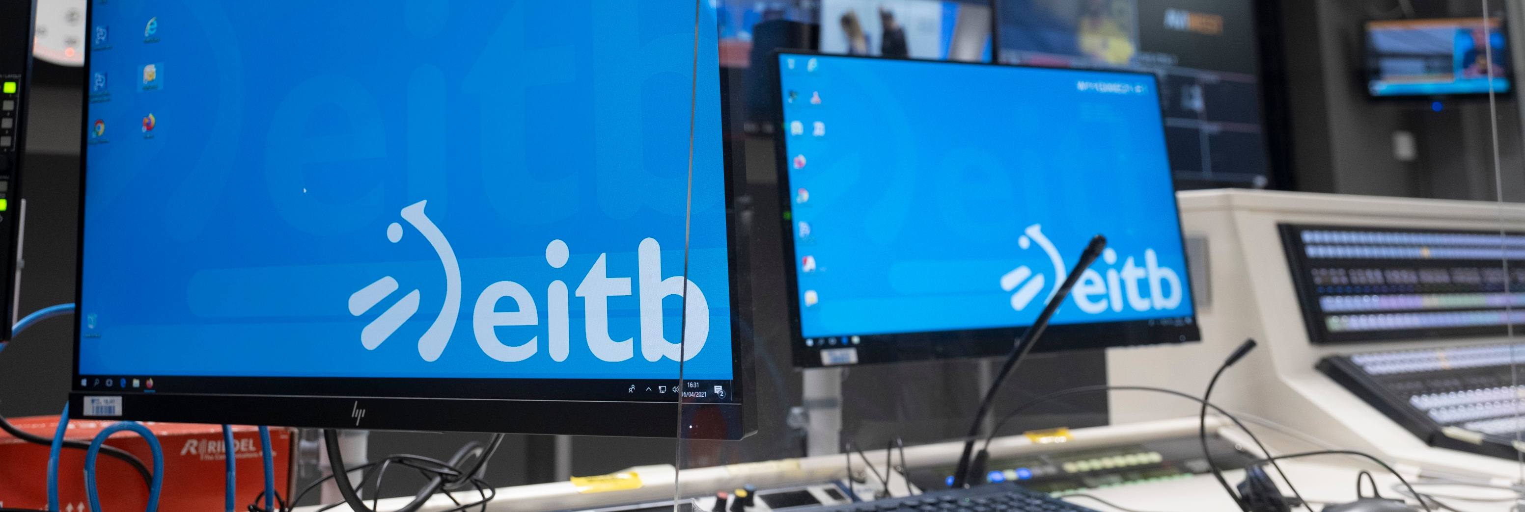 Dos ordenadores con el logotipo de EITB como fondo de pantalla